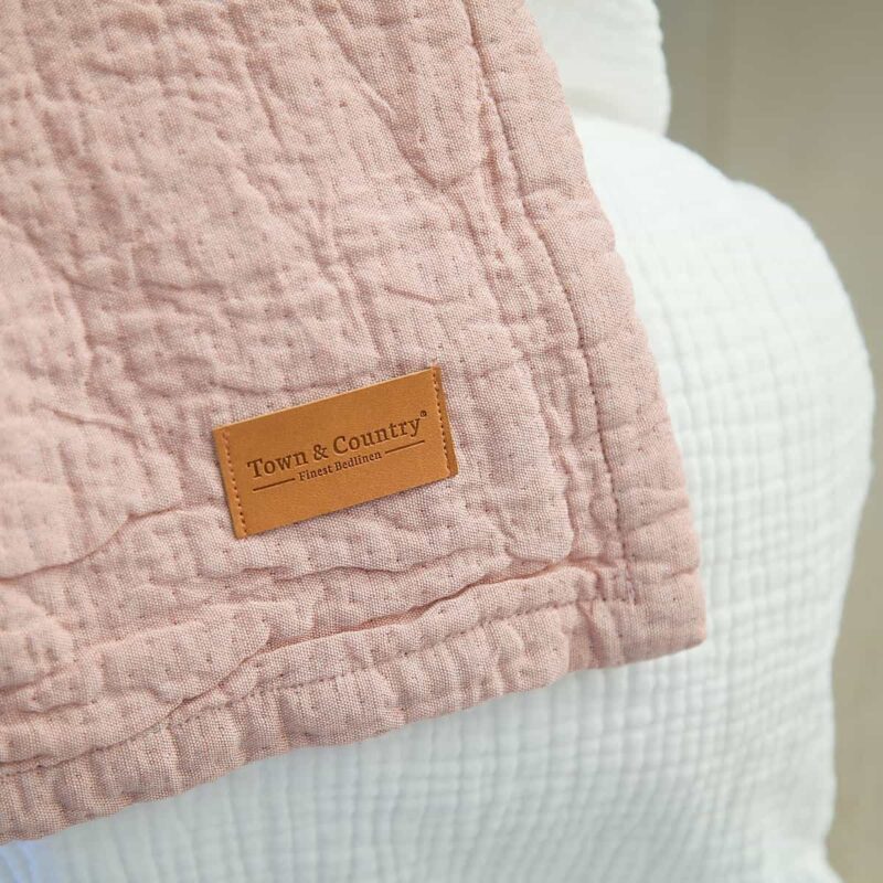 sprei oud roze op een bed met houten vloer