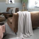 woonkamer met bruin leren bank en lichtgrijze luchtige deken in grijs