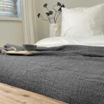 bed met witte dekbedhoes en antraciet bedsprei