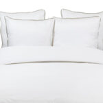 wit dekbed met witte kussens en lint in beige