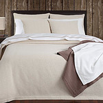 houten muur, opgemaakt bed met ecru bedsprei