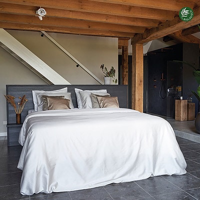 slaapkamer met houten balken plafond en bed met biologisch katoen dekbedovertrek