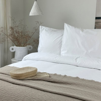 bed met sprei en wit katoenen dekbedovertrek