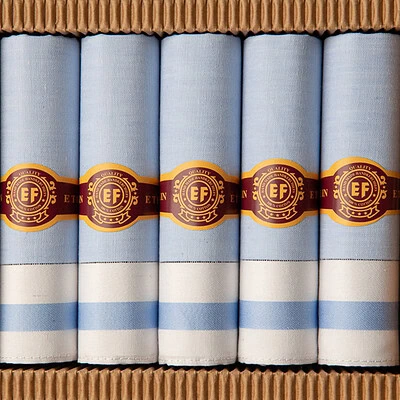 lichtblauwe heren zakdoeken opgerold in sigarendoosje